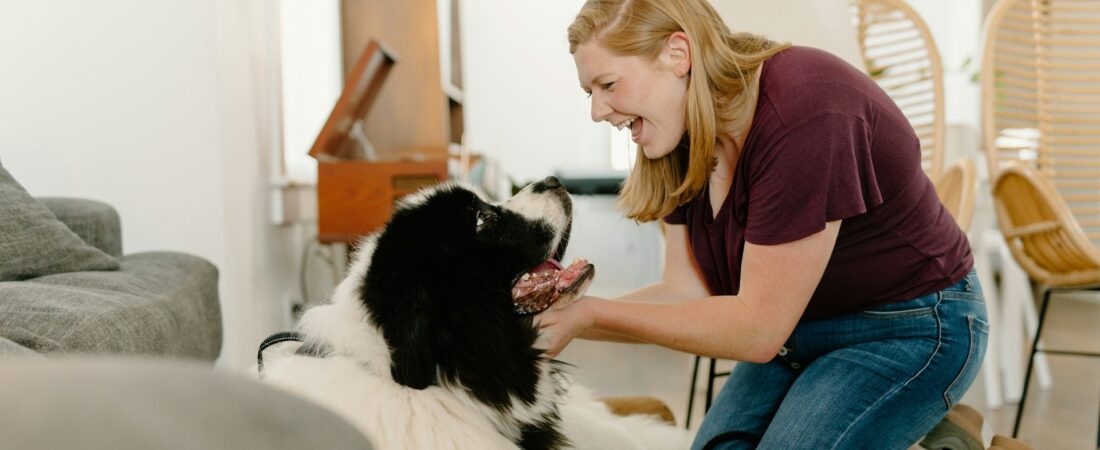 a blonde woman playing with her pet dog at home